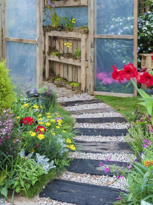 Taman dengan jalan setapak batu alam di antara tanaman